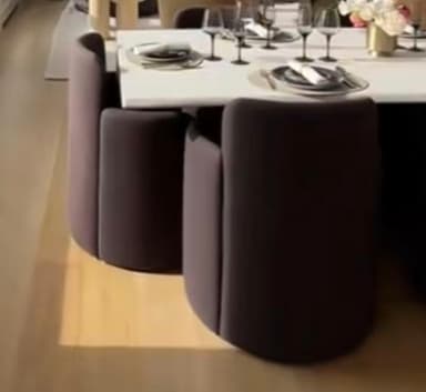 A modern armchair with a curved backrest and integrated armrests. The seat and base are cylindrical, creating a compact and enveloping form. The upholstery has a subtle textured finish. — 3D model
