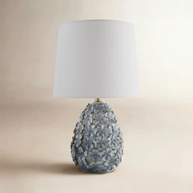 A decorative table lamp featuring a white tapered drum shade and an ornate ceramic base adorned with numerous three-dimensional light blue flowers. — 3D model