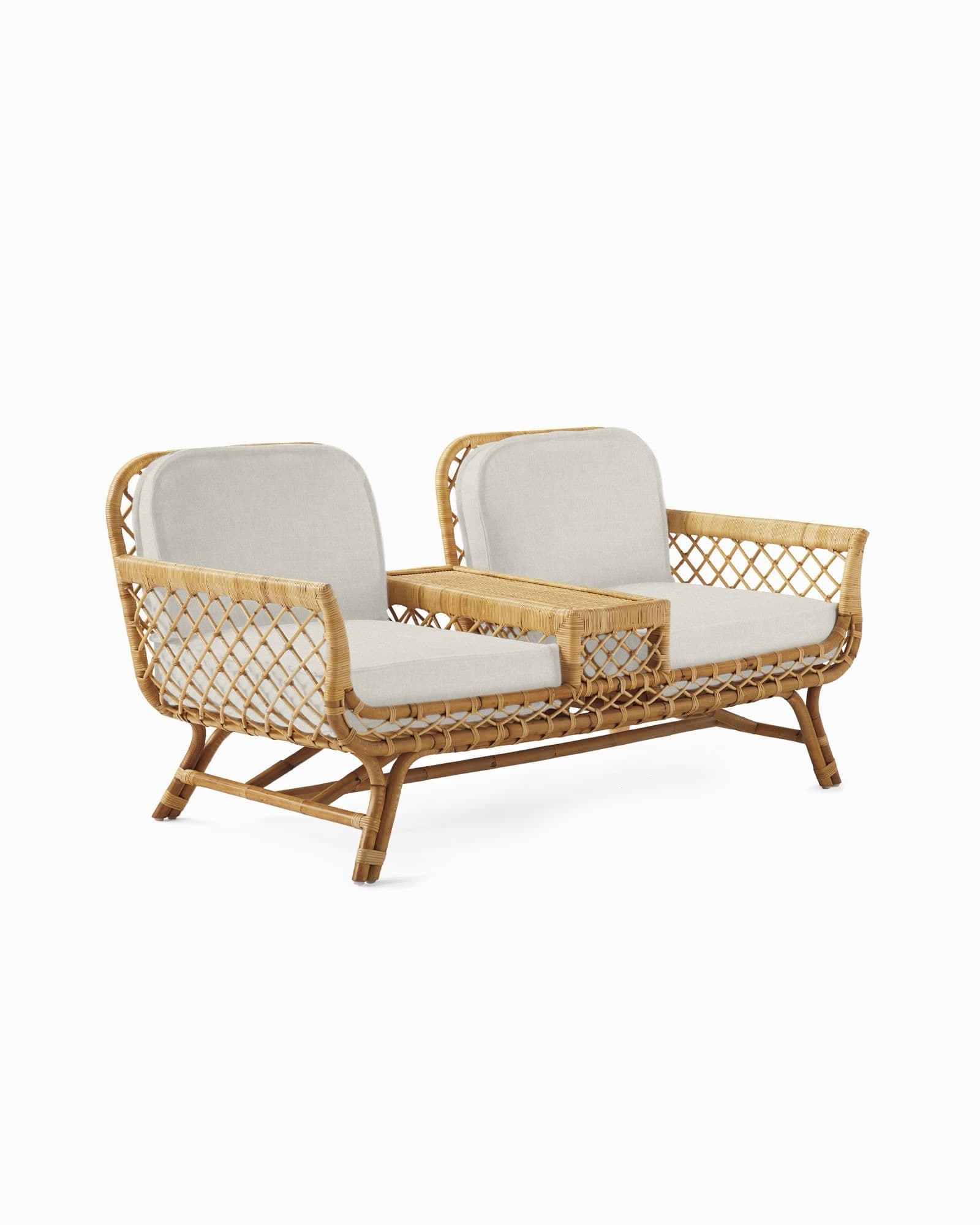 A contemporary loveseat crafted from natural rattan, featuring a woven open-patterned frame. It includes two seating areas with thick, light-colored fabric cushions, separated by a rectangular integrated table section made of solid rattan. The frame showcases curved lines and sturdy legs, presenting a light and airy aesthetic suitable for various relaxed settings. — 3D model
