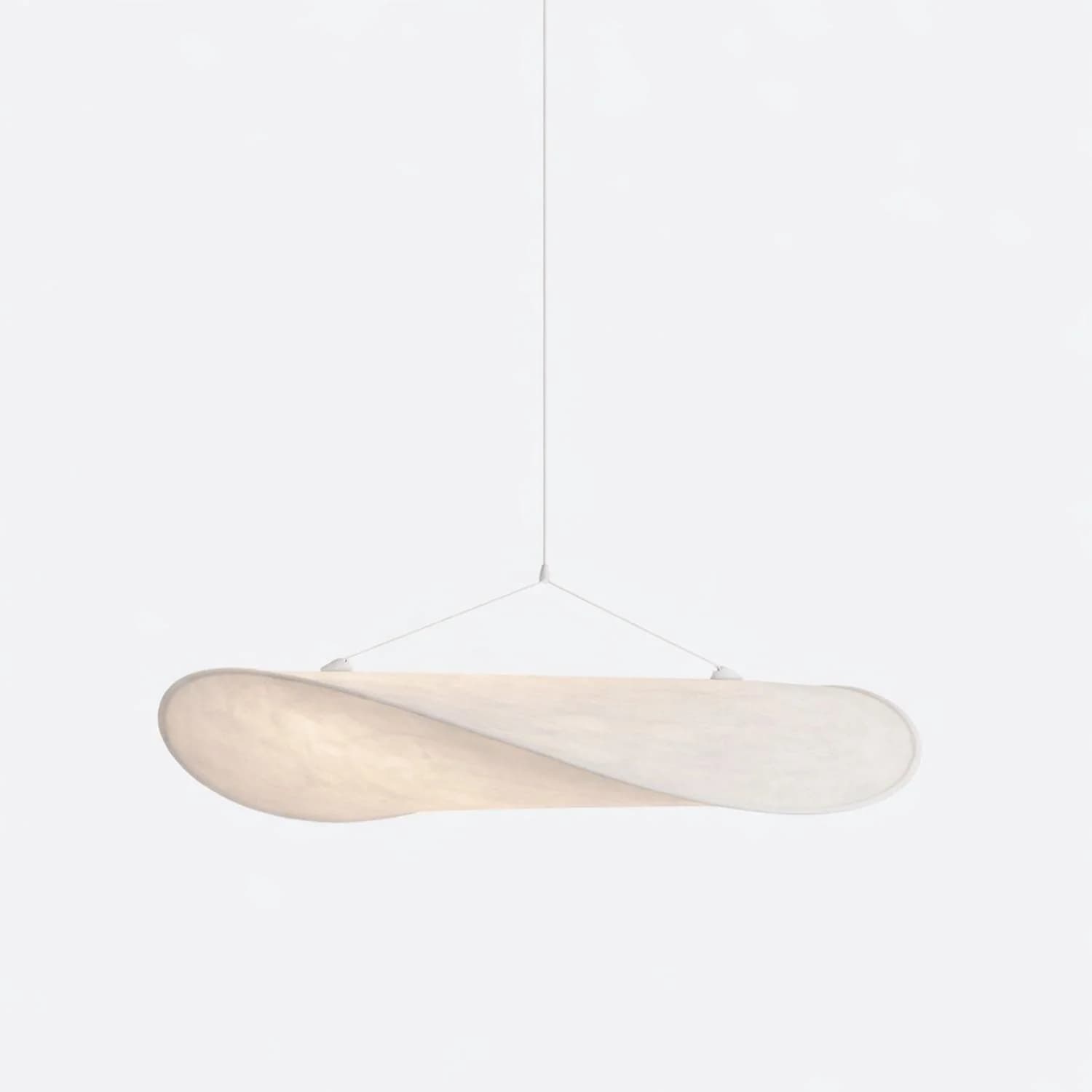 A contemporary pendant light featuring a unique, organically shaped shade that appears to be crafted from a diffused, textured fabric material. The shade has a flattened, elongated oval form with a subtle twist or wave, suggesting movement and softness. It is suspended by thin, nearly invisible wires from a central point, creating a minimalist and ethereal aesthetic. The light source within emits a warm, ambient glow, diffused evenly by the translucent shade. The overall design is elegant and sculptural, intended to be a focal point in a modern interior. — 3D model