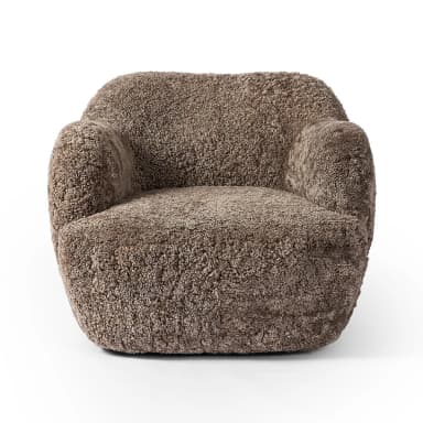 A plush, upholstered armchair with a rounded, organic silhouette. The piece features a thick, textured covering resembling sheepskin or a similar natural fiber, providing a soft and inviting appearance. The armrests are integrated into the body of the chair, flowing seamlessly into the back and seat. The base is low and broad, contributing to its sturdy and comfortable design. — 3D model