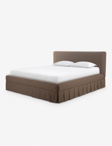 A contemporary upholstered platform bed featuring a soft, rounded headboard and a matching base with an integrated pleated bed skirt. The bed is rendered with a white mattress and two white pillows, suggesting a complete sleep system. The upholstery has a textured, fabric appearance in a neutral brown or taupe color. — 3D model