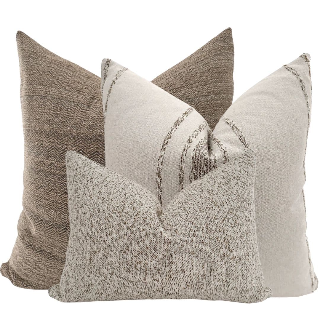 A textured pillow with a speckled pattern, featuring a neutral color palette. It is designed with a slight taper towards the corners, giving it a classic lumbar pillow shape. The fabric appears to be a woven textile. — 3D model