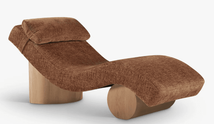 A contemporary chaise lounge with a curved, ergonomic design. It features a rounded wooden base that provides support and a smooth, upholstered surface for comfort. The upholstery is a textured fabric in a warm brown hue, and a matching headrest pillow is attached to the upper end. — 3D model