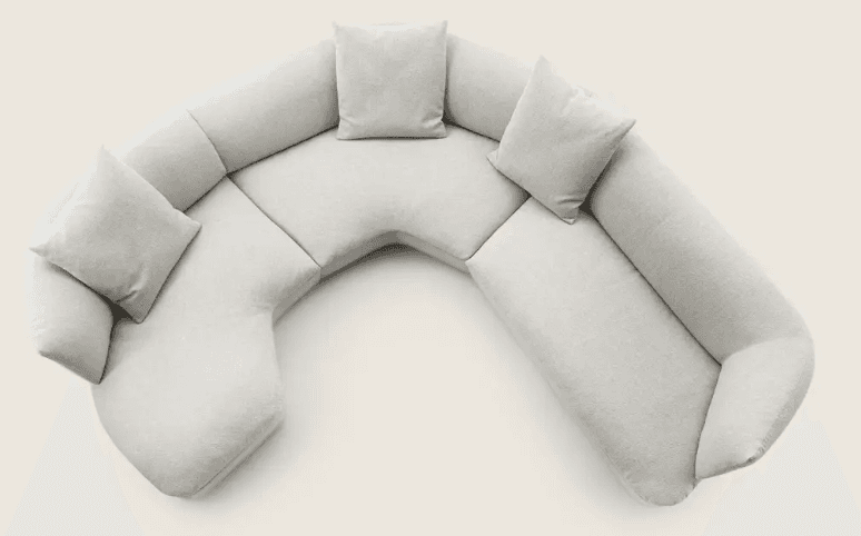 A sectional sofa with a curved, modular design, upholstered in a light-colored, textured fabric. The sofa features multiple seating sections and detached cushions for comfort. It is arranged in a semi-circular configuration, suggesting it is designed for a corner or open-plan space. — 3D model