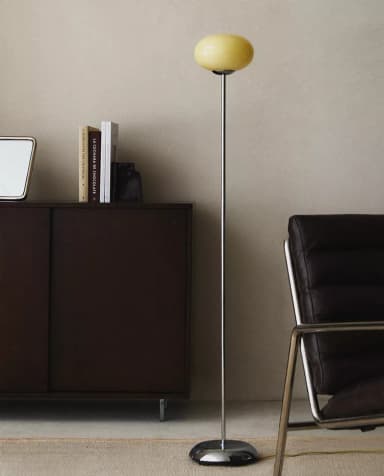 A modern floor lamp with a slender, polished metal stem rising from a circular, reflective base. Topped with a spherical, opaque lampshade in a pale yellow hue, it emits a soft, diffused light. The overall design is minimalist and elegant. — 3D model