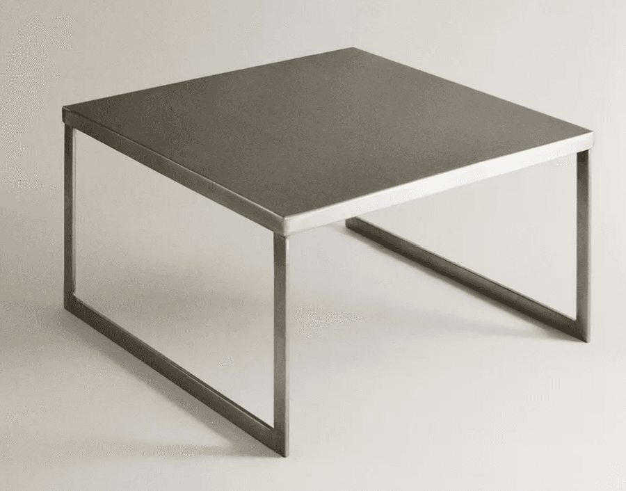 A minimalist square coffee table crafted entirely from metal, featuring a brushed or matte finish. The design consists of a flat, square top supported by two L-shaped metal frames that serve as legs and a base, creating an open and contemporary aesthetic. — 3D model