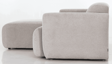 A sofa viewed from the back, featuring a neutral-toned fabric upholstery. The sofa appears to have a modern design with rounded armrests visible on the sides. The back is divided into two distinct cushioned sections, separated by a vertical seam. Small, dark-colored feet are visible at the base. A small, light-colored tag with an emblem is attached to the lower corner of the right side. — 3D model