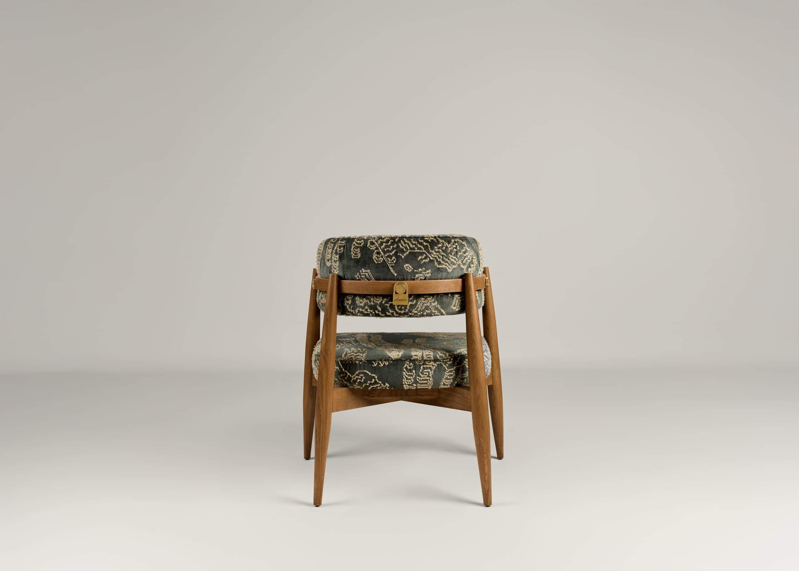 A wooden accent chair with two upholstered seating surfaces. The frame is constructed from light brown wood with tapered legs. The upholstery is a dark fabric with an intricate, possibly embroidered, pattern in a lighter color, featuring scrollwork and geometric motifs. A brass-colored latch or buckle detail is visible on the upper upholstered section. — 3D model