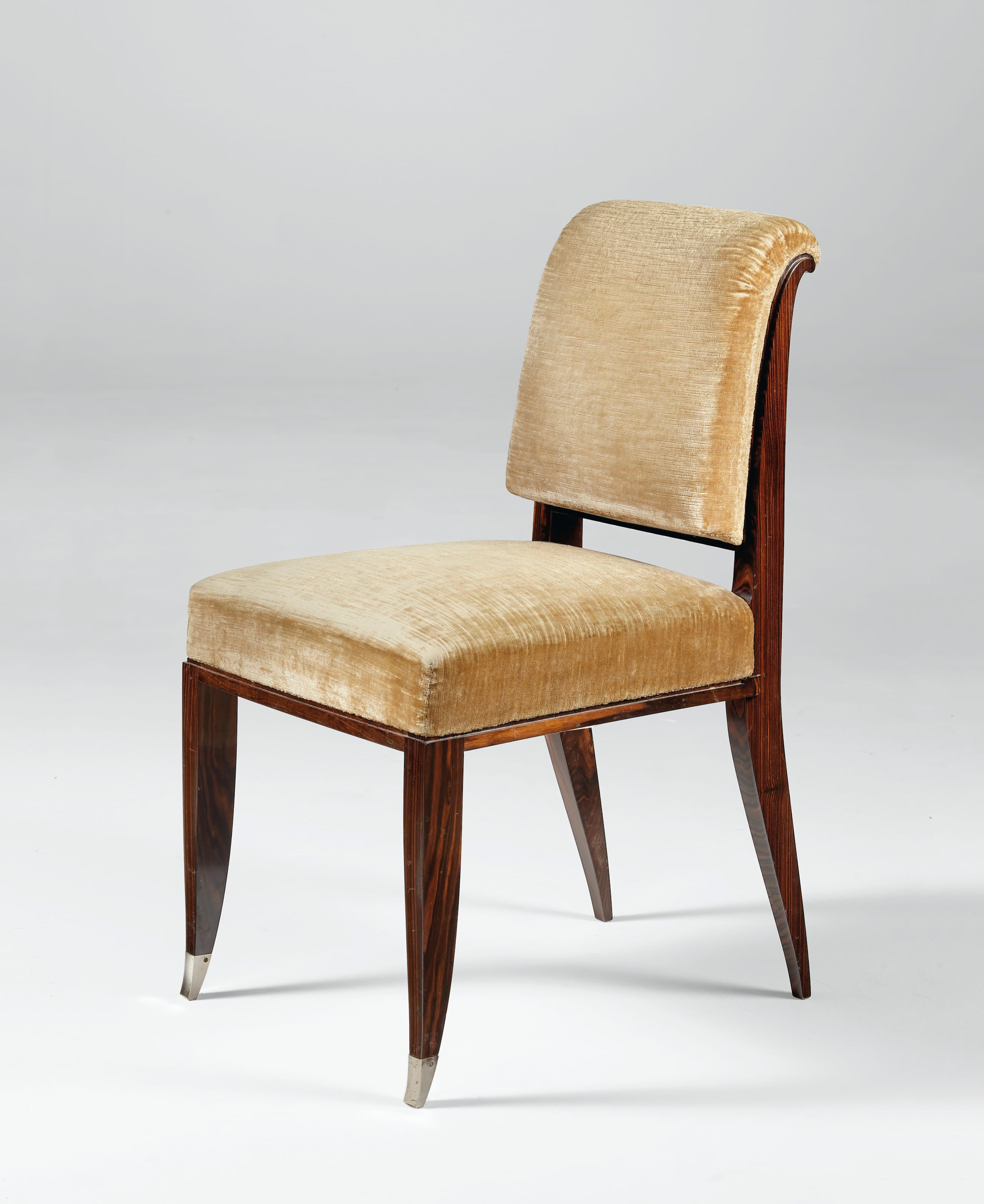 A vintage upholstered chair with a dark wooden frame and a curved backrest. The seat and backrest are covered in a textured, light gold velvet fabric. The wooden legs are slender and tapered, with decorative metal caps at the base of the front legs. The backrest has a distinctive dark wood panel inset. — 3D model