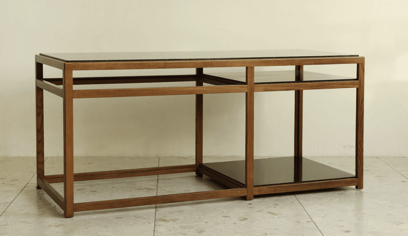 A rectangular coffee table featuring a clear, linear wood frame and two dark, possibly smoked, glass surfaces. The top surface extends across the entire length of the table, while a smaller, square-shaped glass shelf is integrated into the right-hand side of the lower section of the frame. The wooden frame is constructed with clean, straight lines, creating an open and airy aesthetic. The table appears to be in excellent condition, showcasing a modern or contemporary design. — 3D model