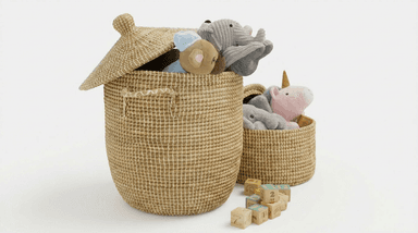 Two woven storage baskets of differing sizes, filled with plush toys and surrounded by wooden building blocks. The larger, taller basket features a fitted, domed lid and integrated handles, while the smaller basket is open-topped. Both baskets are constructed from a natural-colored woven fiber with a distinct crisscross pattern, appearing to be in excellent condition. — 3D model