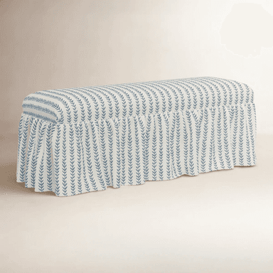 A rectangular bench upholstered with a fabric featuring a repeating pattern of blue vertical sprigs on a cream background. The bench has a skirted base with a ruffled edge that extends to the floor, concealing the legs. The upholstery has a plush, padded appearance. — 3D model