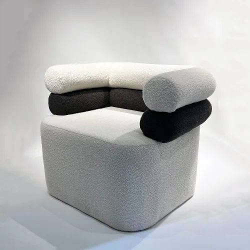 A modern armchair with a modular design. The base is a solid, rounded cube upholstered in a textured light gray fabric. The backrest and armrests are constructed from large, cylindrical cushions stacked in alternating colors of white, dark gray, and black, all upholstered in a similar textured fabric. — 3D model