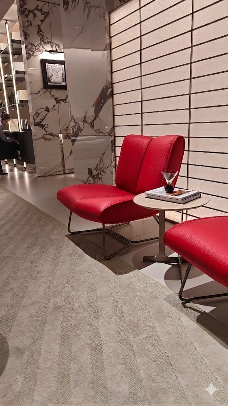 A modern armchair with a low profile and a unique geometric metal base. The seat and backrest are upholstered in red material and feature a quilted or stitched design. — 3D model