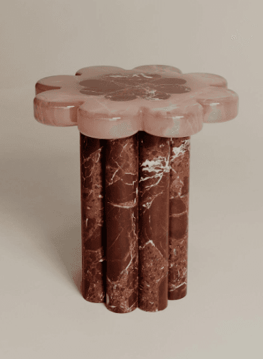 A side table with a top shaped like a flower, featuring multiple rounded petals. The top appears to be constructed from two different types of marble: a lighter pinkish-white marble for the outer petals and a darker, reddish-brown marble with white veining for the central portion. The base consists of several fluted, cylindrical columns, also made from the reddish-brown marble with white veining, arranged closely together. — 3D model