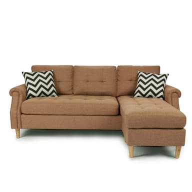 A contemporary L-shaped sectional sofa with a chaise lounge, upholstered in a camel-colored woven fabric. It features classic rolled armrests, button-tufted seat and back cushions, and is supported by light-finished tapered wooden legs. Two decorative throw pillows with a black and white chevron pattern are included. — 3D model