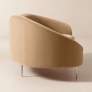 A modern curved back sofa upholstered in plush, champagne-colored velvet, featuring slender, polished stainless steel legs with a champagne finish. — 3D model