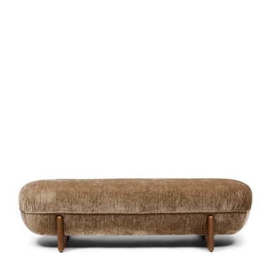 A low-profile, elongated bench with a rounded, upholstered form and solid wood legs. The upholstery features a textured, velvet-like fabric in a neutral tone, exhibiting subtle creasing that follows the rounded shape. The legs are triangular in cross-section and appear to be made of a dark wood with a visible grain. — 3D model