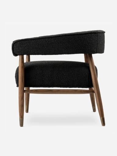 A modern upholstered accent armchair featuring a black bouclé fabric, a solid wooden frame, and tapered legs with brass caps. — 3D model