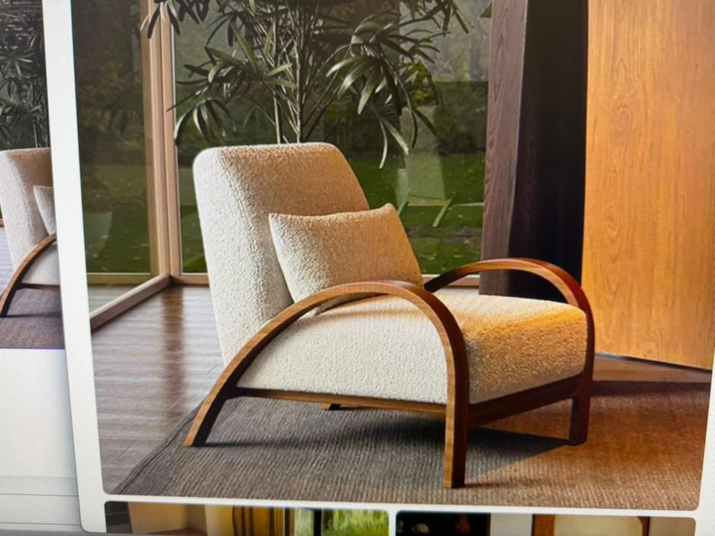 A contemporary lounge chair featuring an off-white boucle upholstered seat and backrest, complemented by a distinctive dark bentwood frame that forms integrated armrests. The chair includes a matching lumbar pillow. — 3D model