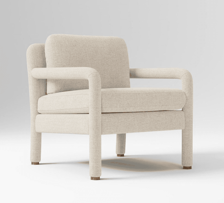 A contemporary armchair upholstered in a light-colored, textured fabric. It features a boxy silhouette with thick, rounded arms that curve downwards and a low-profile backrest. The seat and back cushions appear to be separate. The chair is supported by four sturdy legs, each capped with a small wooden foot. — 3D model