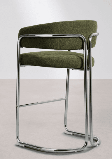 A tall bar stool featuring a bent tubular chrome frame and upholstered seat and backrest. The frame forms a continuous loop creating a sled base and supports the seat and back. The seat and back are cushioned and covered in a textured olive green fabric, with the back curving around to form integrated armrests. A horizontal chrome bar serves as a footrest. The design reflects a modernist aesthetic. — 3D model