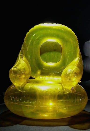 An orange, translucent inflatable armchair resembling a balloon. It has a rounded seat and a curved backrest. The surface shows creases and reflections, indicative of an inflated material. A valve is visible on the seat cushion. — 3D model