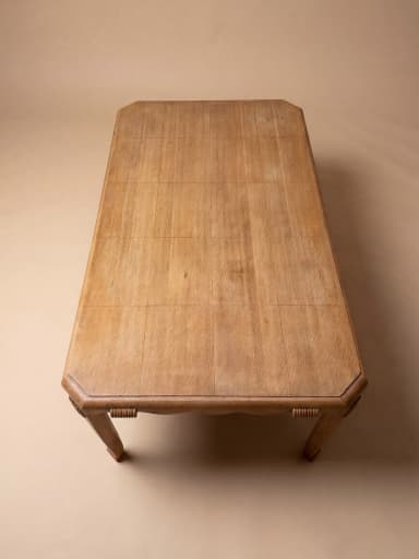 A rectangular dining table crafted from oak wood, featuring a distinctive scalloped apron and decorative carved embellishments on its corners. The table stands on four tapered legs with a subtle curve, reflecting an Art Deco or transitional design. — 3D model