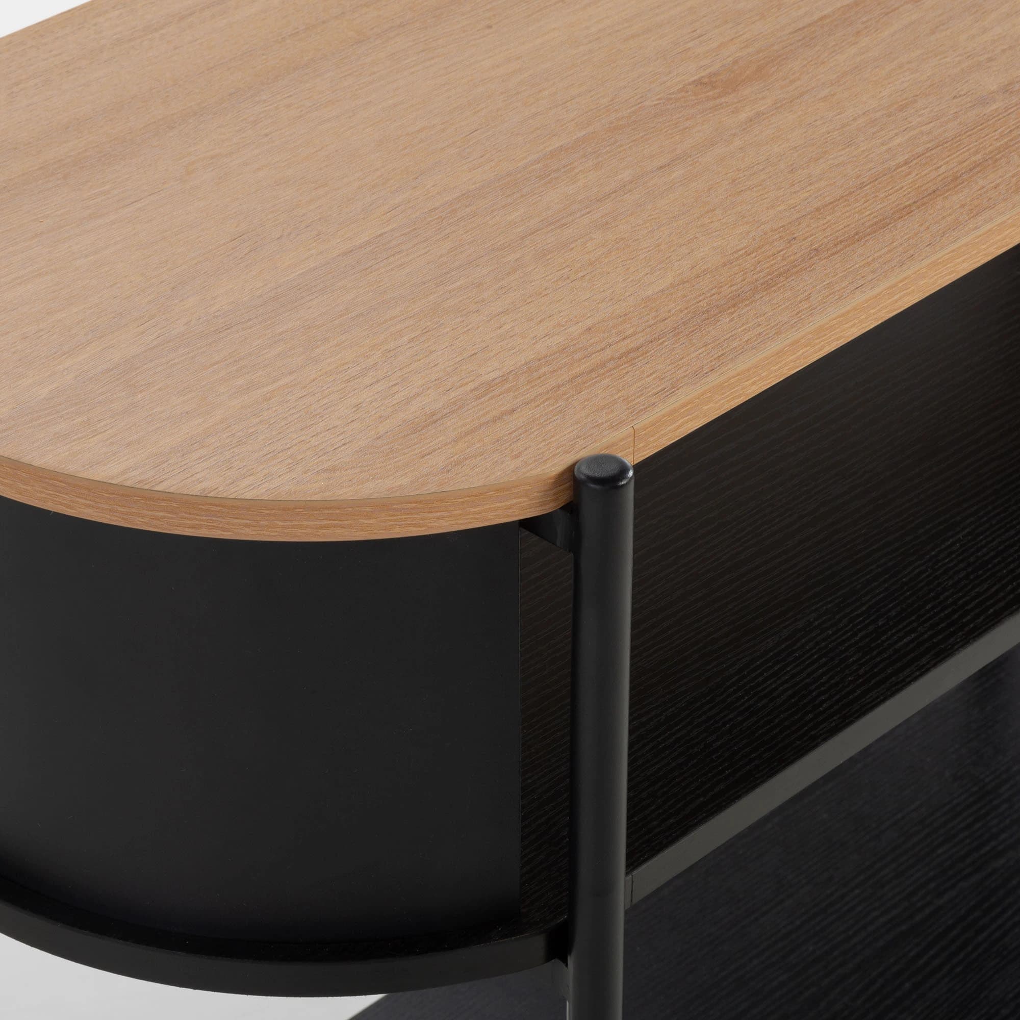 A close-up view of a modern two-tier side table, featuring a light-colored wood tabletop with rounded edges. Below the top, a curved black panel suggests integrated storage or a design enclosure. The table is supported by black vertical cylindrical legs, which also connect to a lower, dark wood-grain shelf, emphasizing a minimalist and contemporary aesthetic. — 3D model
