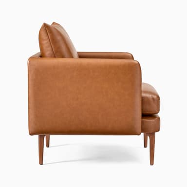 A modern armchair upholstered in brown leather. It features a boxy frame with rounded armrests and a slightly reclined backrest. The seat is composed of two thick cushions. The armchair is supported by four tapered wooden legs, angled outwards. — 3D model