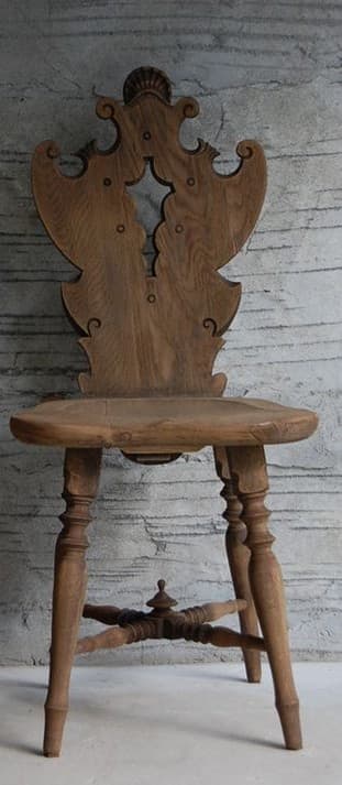 A highly decorative wooden side chair featuring elaborate carving on its backrest, a sculpted seat, and turned legs. The chair is made of light-colored wood, possibly oak, with a natural finish. — 3D model