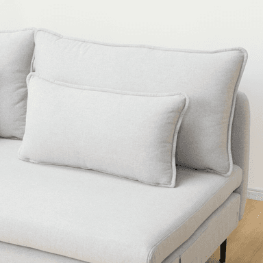A contemporary armless chaise loveseat, upholstered in a light gray textured fabric. It features a low-profile design with a deep, elongated seat on the right side, resembling a chaise. The seating is supported by minimalist black metal legs, and the piece includes two large back cushions and two smaller rectangular throw pillows, all with subtle piped edges. — 3D model