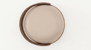 A compact, round, contemporary stool or ottoman. It features a two-tone upholstered body, with a lighter beige on the upper section and a warmer caramel brown on the lower, bulbous base. A thin wooden trim separates the two leather sections. A prominent, curved wooden handle in a dark wood tone arches gracefully over the top, creating a sculptural element and an opening beneath it. — 3D model