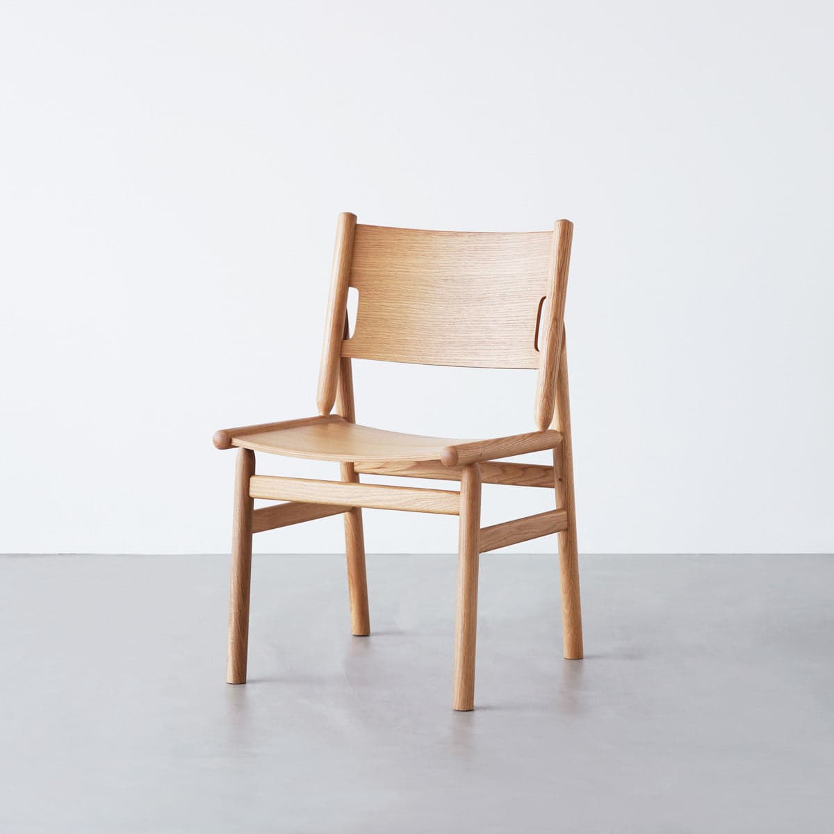 A minimalist wooden chair with a curved backrest and a contoured seat. The chair features a simple construction with visible joinery and a light wood grain. — 3D model