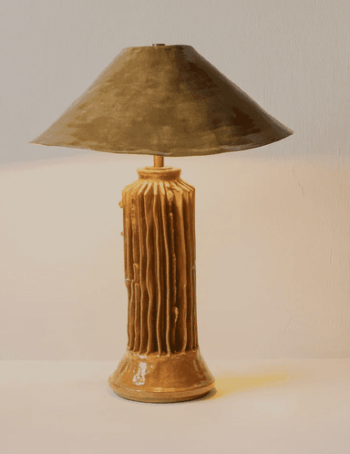 A distinctive table lamp featuring an organically textured ceramic base with vertical ridges and a wide, conical shade, presented in warm bronze tones. — 3D model
