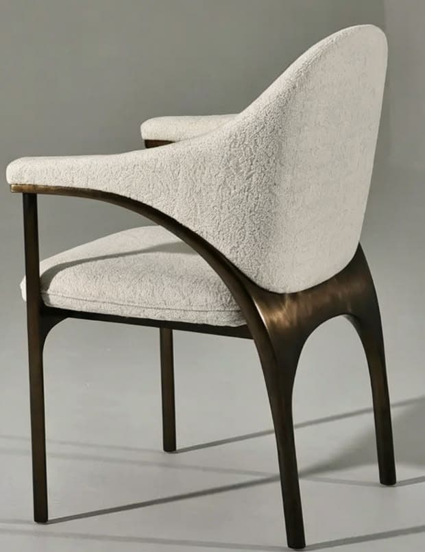 A modern armchair featuring a curved upholstered back and seat, supported by a dark, open wood frame that forms the legs and integrated armrests. The upholstery is a light, textured bouclé fabric. — 3D model
