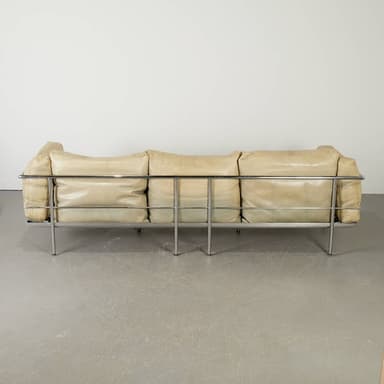 A sectional sofa with a light beige leather upholstery and a chrome frame. The sofa consists of multiple cushion modules, with the back cushions appearing somewhat unstructured and draped. The frame is visible on the sides and forms the legs of the sofa. The overall design suggests a modern or contemporary aesthetic. — 3D model