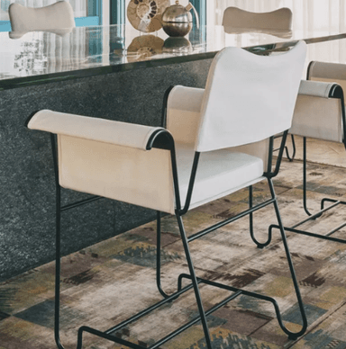 A contemporary armchair featuring a minimalist black metal tubular frame and upholstered seat, back, and armrests. The upholstery is off-white or cream-colored fabric, and the armrests are adorned with a distinctive fringe detail. — 3D model