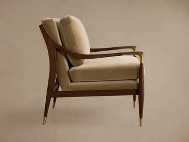 A plush armchair with a wooden frame and velvet upholstery. The armchair features a high back and seat cushions, with elegantly curved wooden arms. Decorative brass accents are present on the armrests and the tapered legs, which are capped with brass. — 3D model