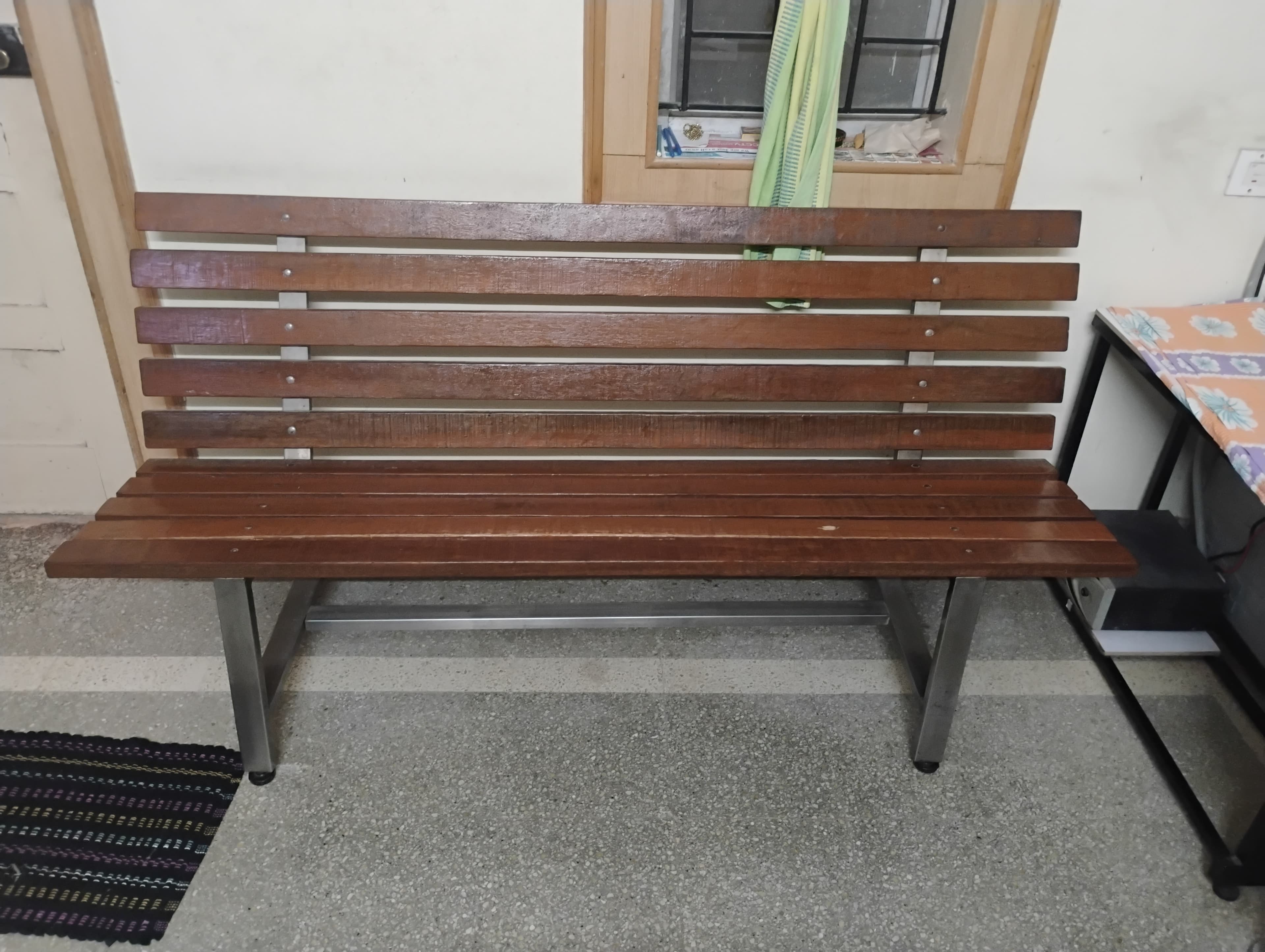 A modern outdoor bench featuring a backrest, constructed from horizontal wooden slats and a silver-colored metal frame. The slats are uniformly spaced and secured to the frame with visible fasteners. The bench design is clean and functional, typical of public seating. — 3D model