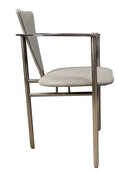 A modern armchair with a tubular metal frame and upholstered seat and backrest. The frame is constructed from polished chrome or stainless steel, featuring cylindrical legs and armrests. The seat and backrest are upholstered in a light-colored fabric with a speckled pattern. The design is minimalist and functional. — 3D model