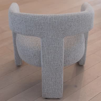 A modern armchair with a curved backrest and straight arms. The chair is upholstered in a textured fabric and features sturdy, rectangular legs. — 3D model