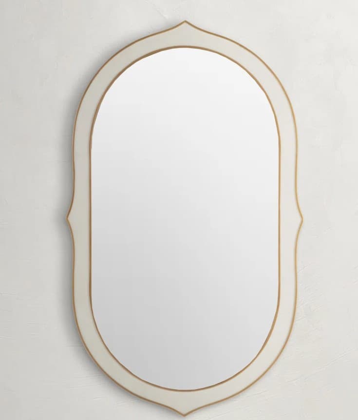 An oval-shaped mirror with a decorative frame. The frame has a smooth, matte finish with a subtle curvature on its outer edges and a smaller, inset decorative element along the inner rim. The mirror's reflective surface is centered within this frame. — 3D model