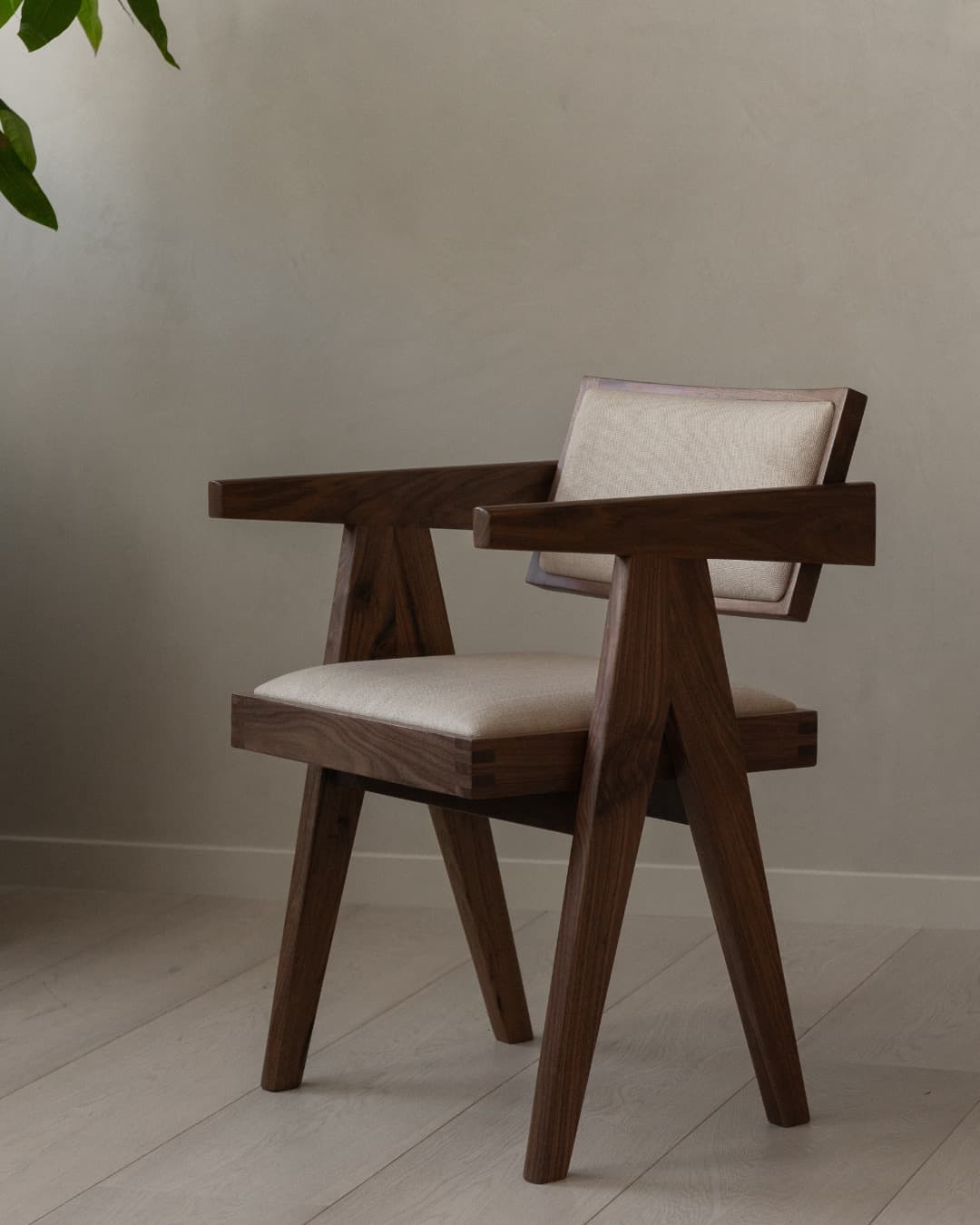 A modern armchair with a wooden frame and upholstered seat and backrest. The frame is constructed from dark wood, likely walnut, with visible joinery details. The legs are angled, and the armrests are flat and wide. The upholstery is a neutral, light-colored fabric. — 3D model