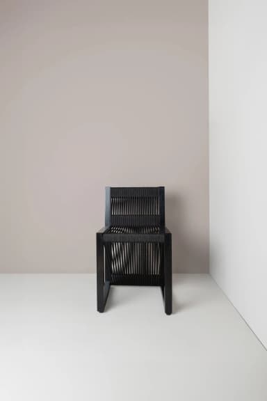 A contemporary chair with a black frame and a seat and backrest constructed from closely spaced black cords or ropes. The cords are stretched vertically across the frame, creating a textured and somewhat visually open surface. The legs are simple, straight, and square in profile. — 3D model
