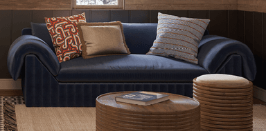 A modern loveseat with deep navy blue upholstery, featuring a distinctive vertically fluted base and soft, rolled-over arms. The seating area includes two seat cushions and a backrest with three assorted throw pillows. — 3D model
