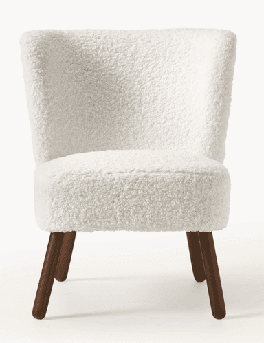 A contemporary armless accent chair featuring a curved back and seat, upholstered in a plush, white bouclé fabric. It stands on four slender, splayed dark wood legs. — 3D model