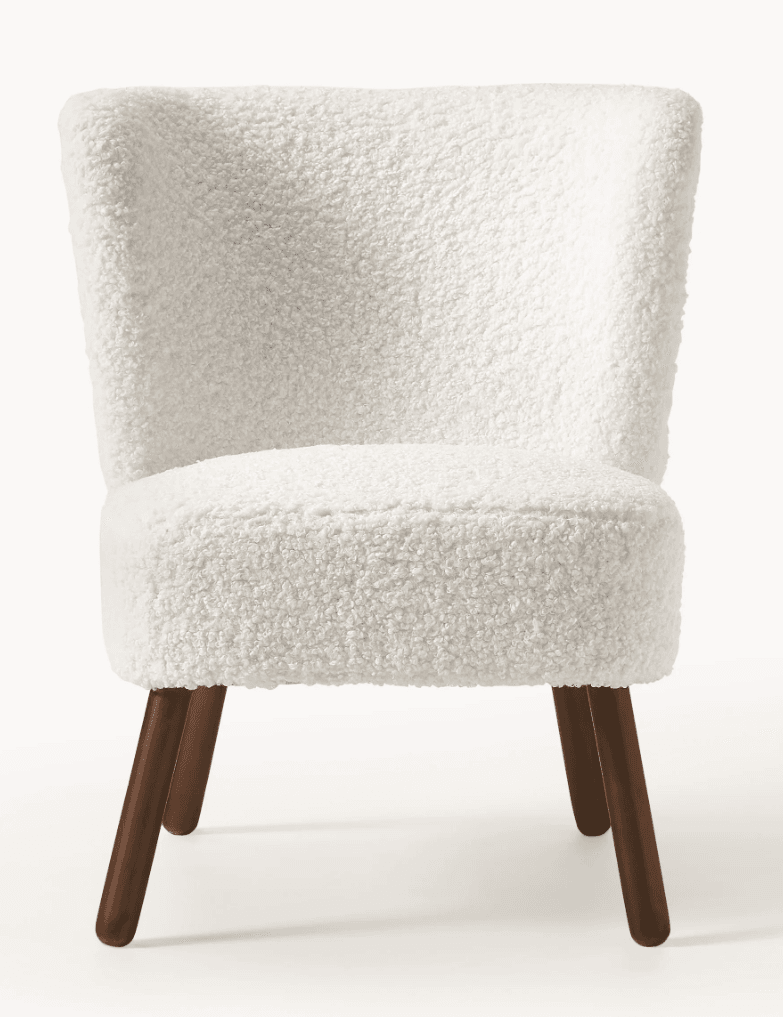 A contemporary armless accent chair featuring a curved back and seat, upholstered in a plush, white bouclé fabric. It stands on four slender, splayed dark wood legs. — 3D model