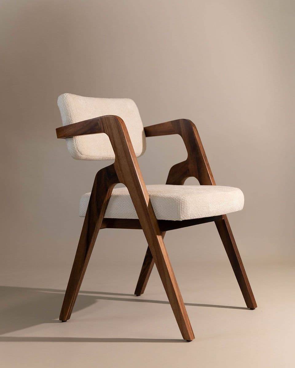 A stylish mid-century modern inspired dining armchair featuring a dark walnut-stained solid wood frame with distinct curved arms and tapered legs. The seat and backrest are upholstered in a light, textured off-white fabric, providing a comfortable and elegant seating solution. — 3D model